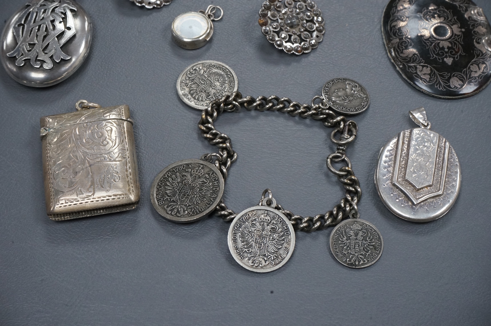 A mixed group of assorted collectables including a silver vesta case, two Victorian white metal lockets, two cut steel buttons, a coin bracelet and three other items.